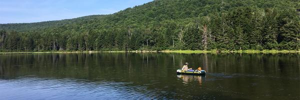 Student in rubber raft on lake